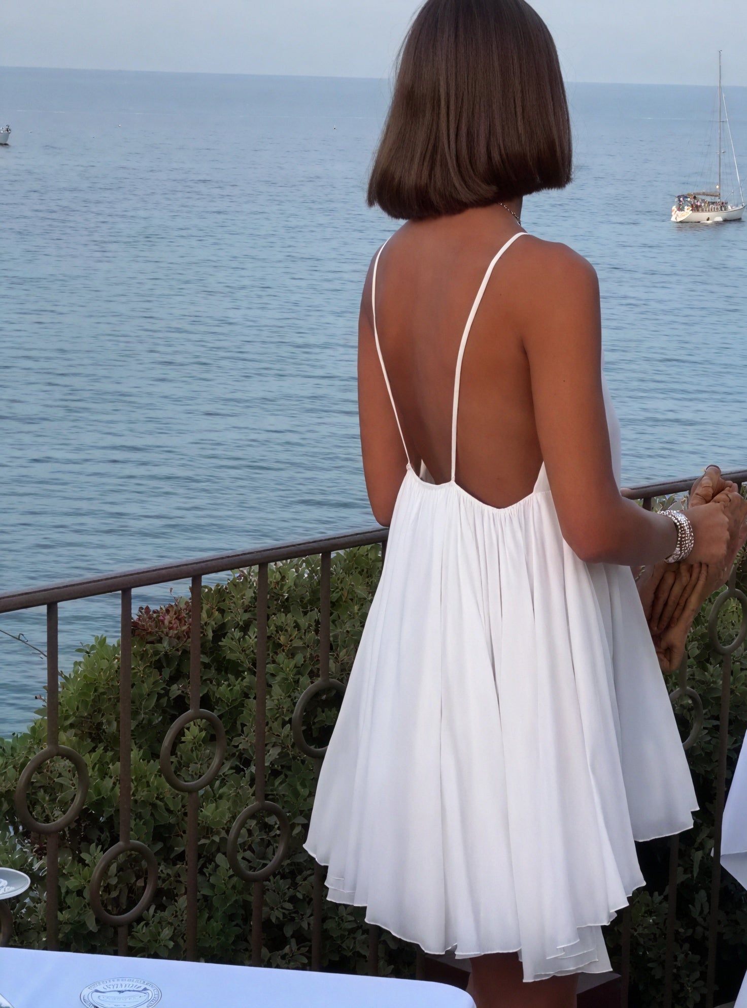Light blue Montaracrest flowy dress with thin spaghetti straps and V-neckline, shown hanging on a wooden hanger.