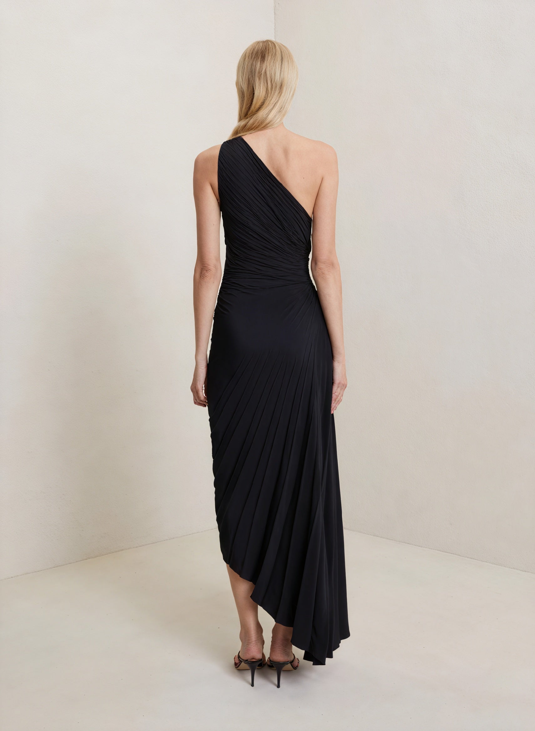 Montaracrest monospalla pleated dress with asymmetric hem, showcasing elegant design and ruffled shoulder detail.