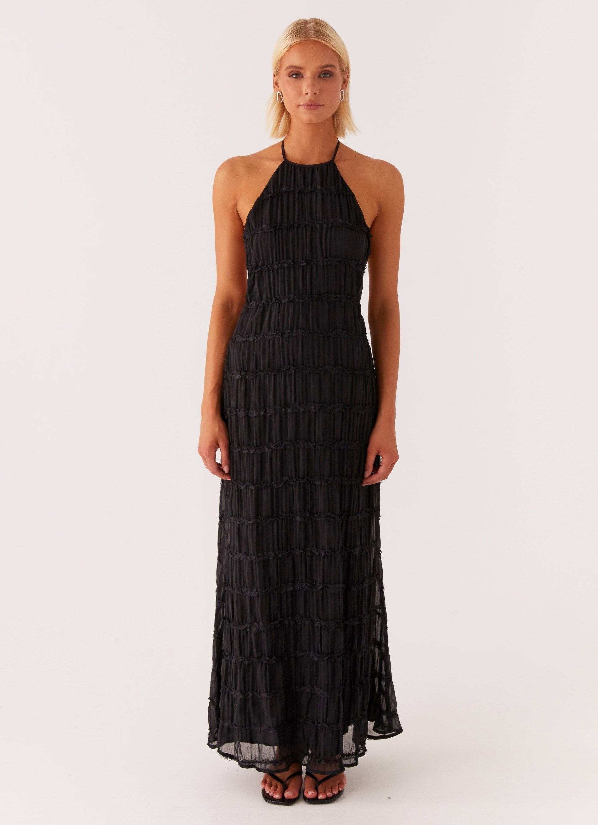 Black Montaracrest Celeste Maxi Dress displayed on a model, featuring a flowing silhouette and elegant design.