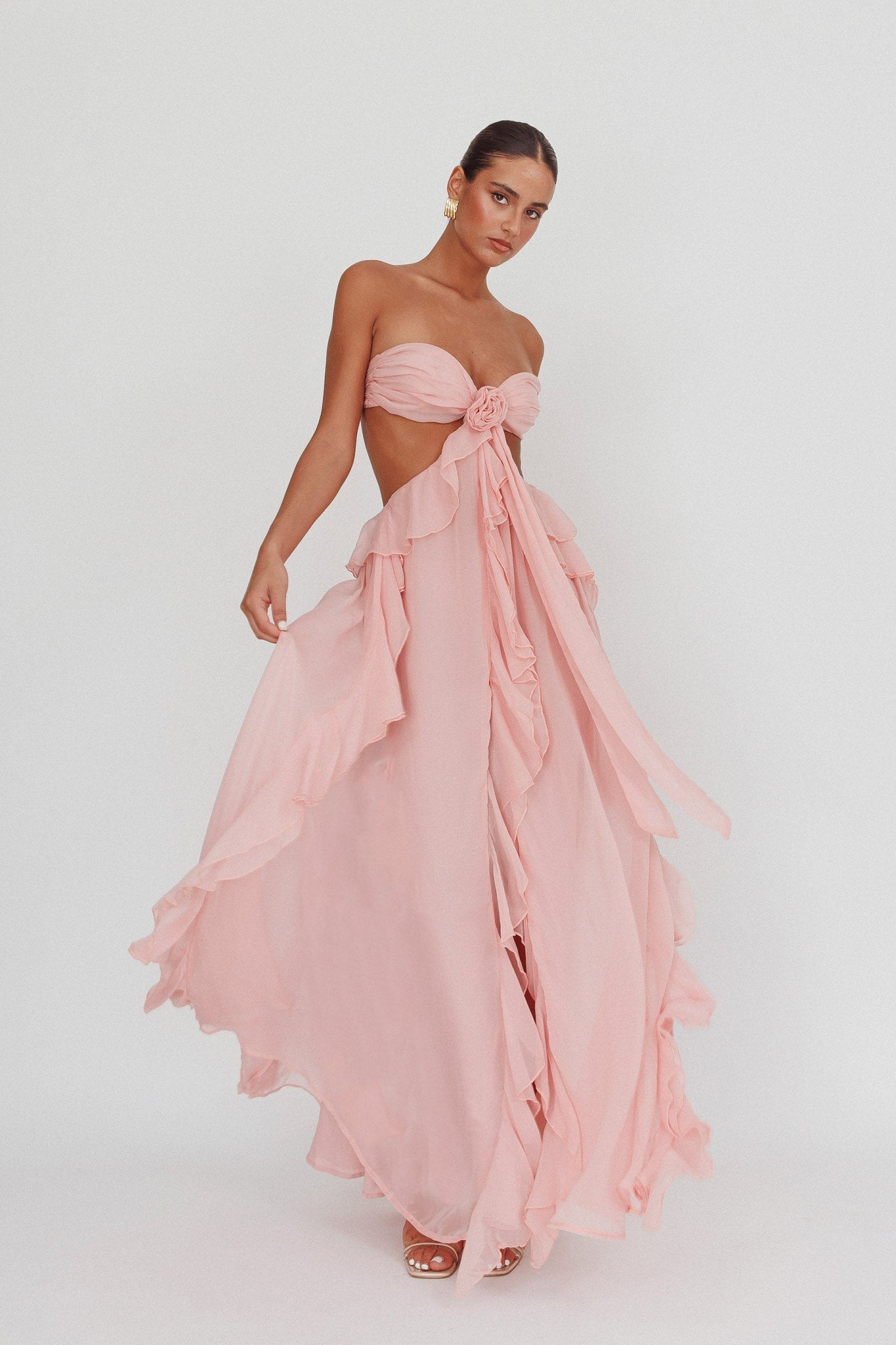 Elegant long sleeveless dress by Montaracrest with cut-out details and flowing ruffle accents, perfect for summer occasions.