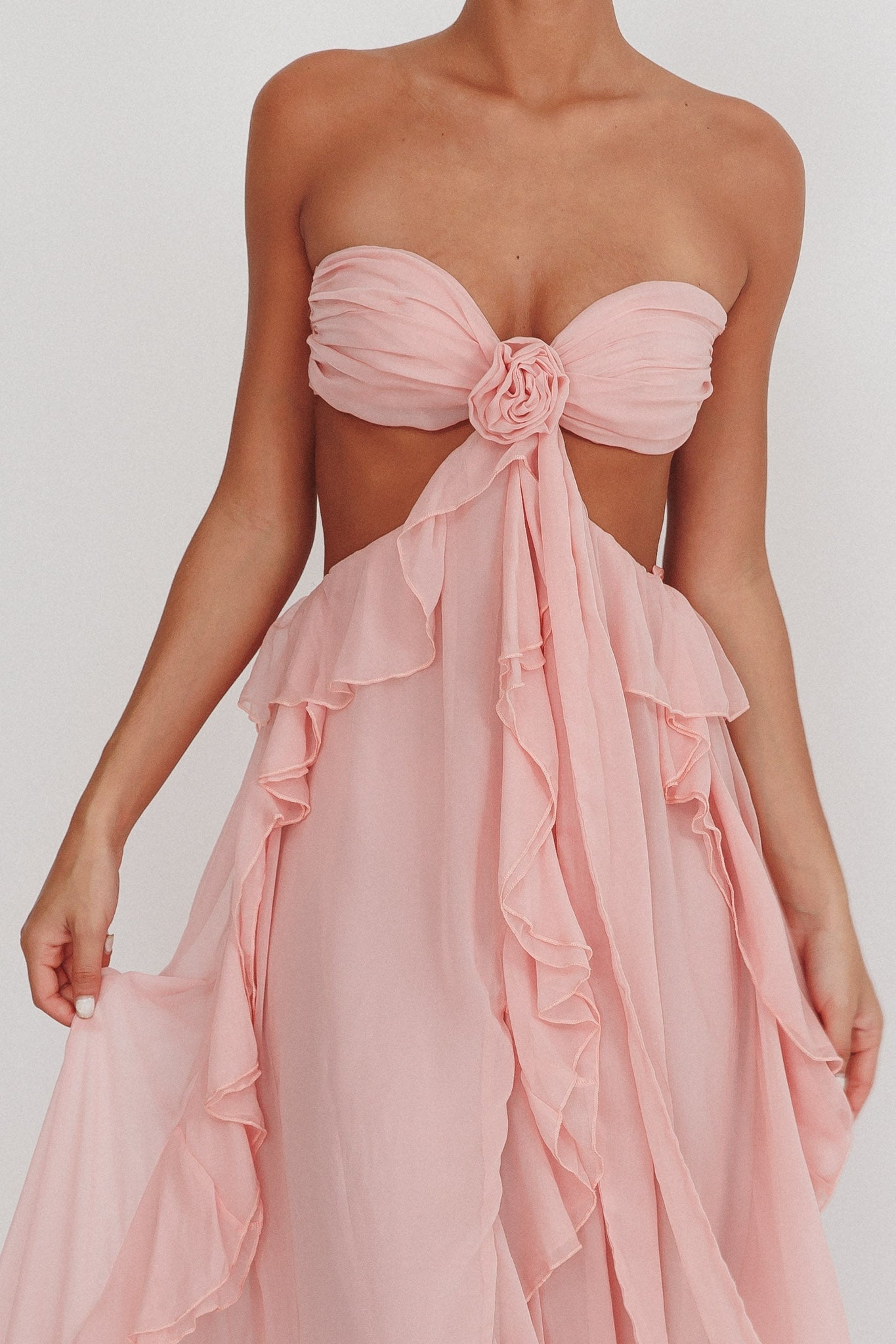 Elegant long sleeveless dress by Montaracrest featuring cut-out details and floating ruffle accents.